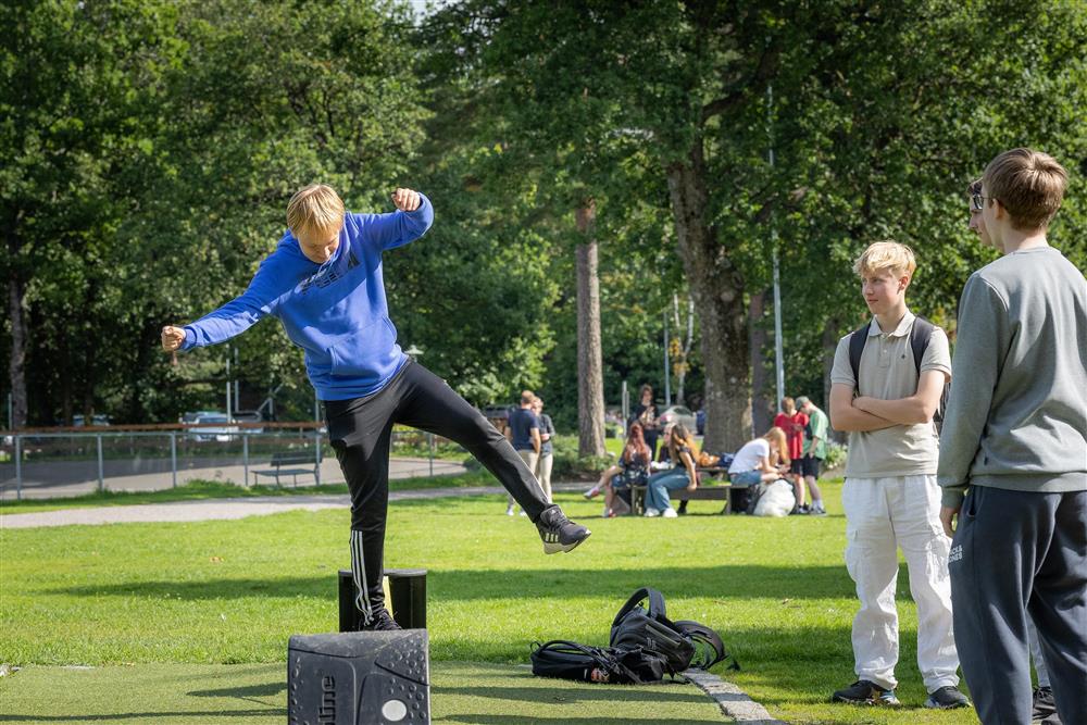 Person som balanserer på line, to personer ser på og ler - Klikk for stort bilde