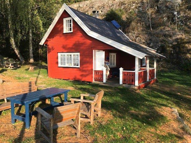 Rød hytte. Det står bord og benker ved hytta. - Klikk for stort bilde