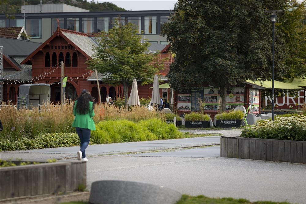 Person som går i gågate foran rød byggning i dragestil - Klikk for stort bilde